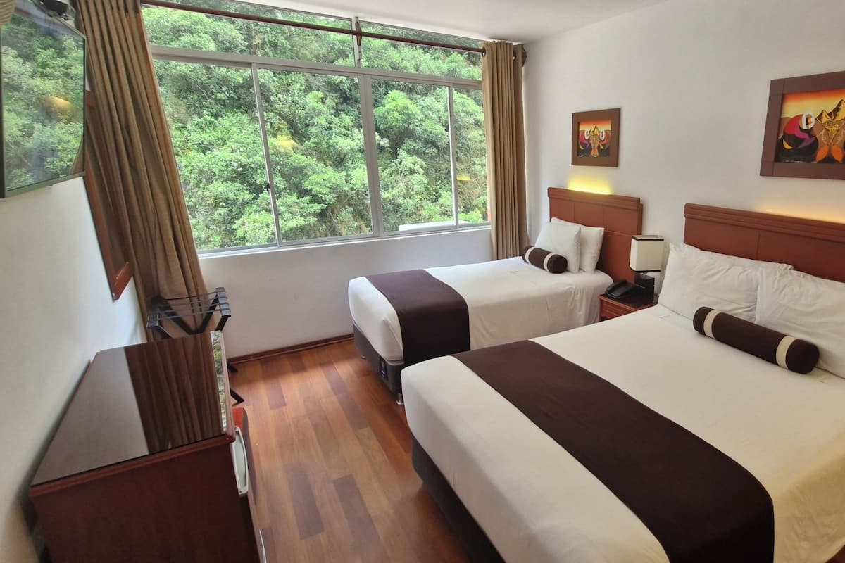 A hotel room with two beds, a large window with curtains, a painting on the wall, and a nightstand with a lamp.