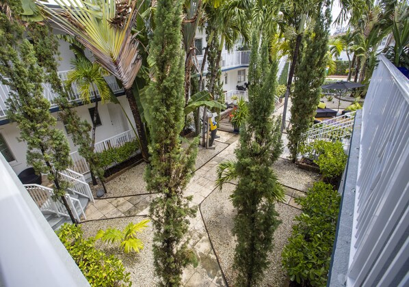 Une cour avec un hamac, des palmiers et un bâtiment doté de balcons.