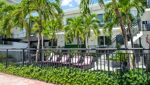 A hotel with outdoor seating, palm trees, and a staircase. - Beachside All Suites Hotel (Miami Beach)
