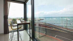 A room with a large window overlooking a coastal road and sea. - Vista View Resort (Jeju City)