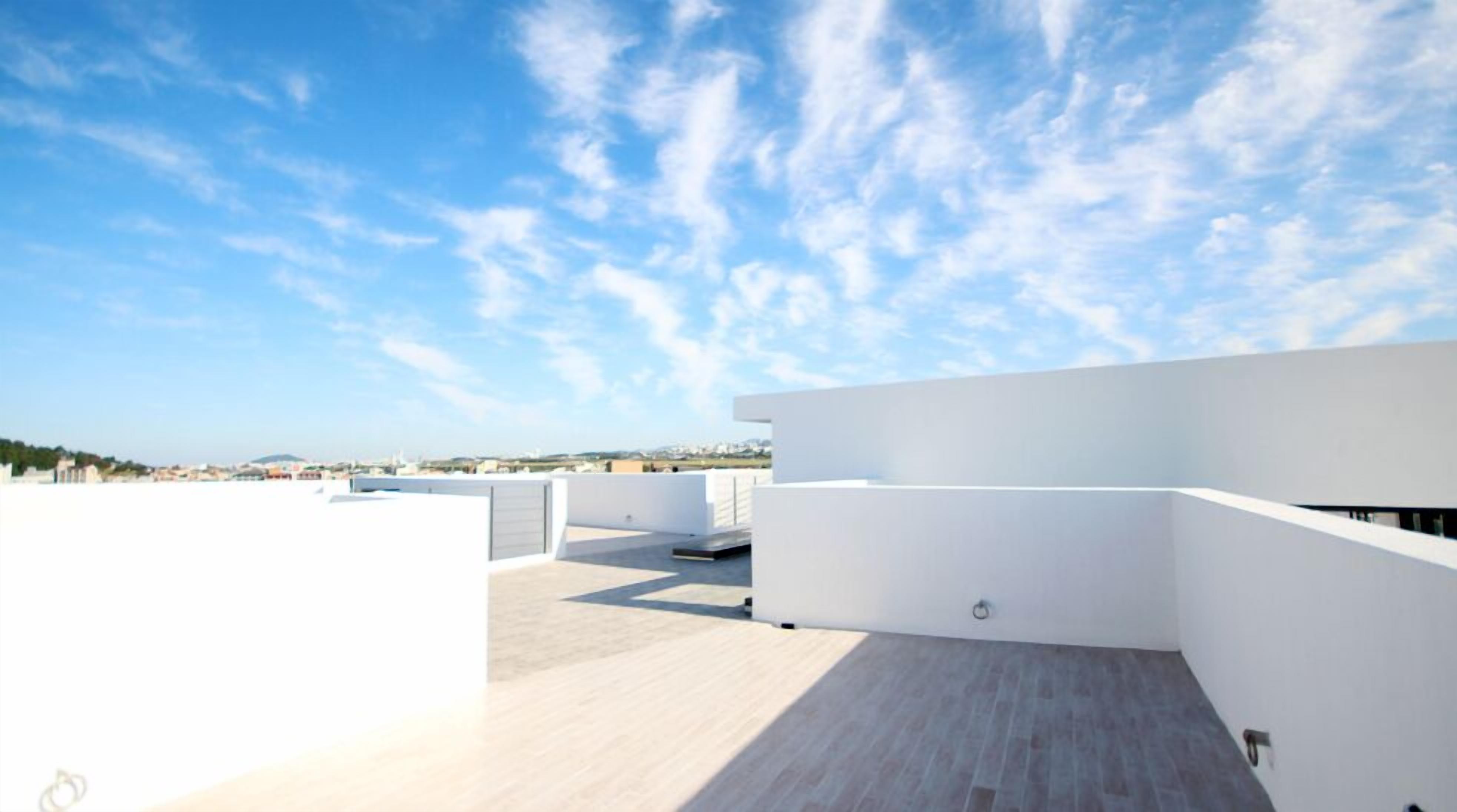 Una terraza en la azotea con vistas despejadas del horizonte urbano, que presenta arquitectura moderna y un piso plano de color claro.