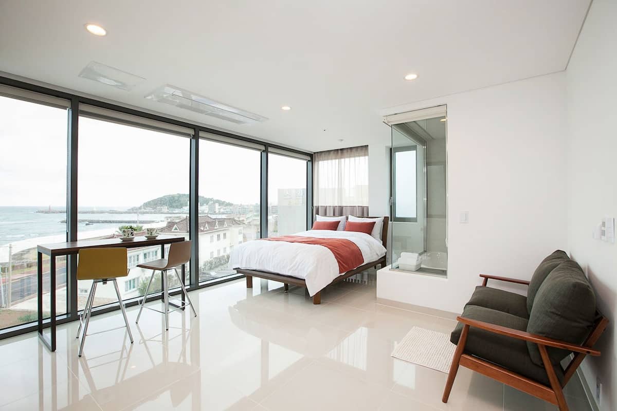 Un dormitorio moderno con una cama grande, un escritorio y vistas al mar.