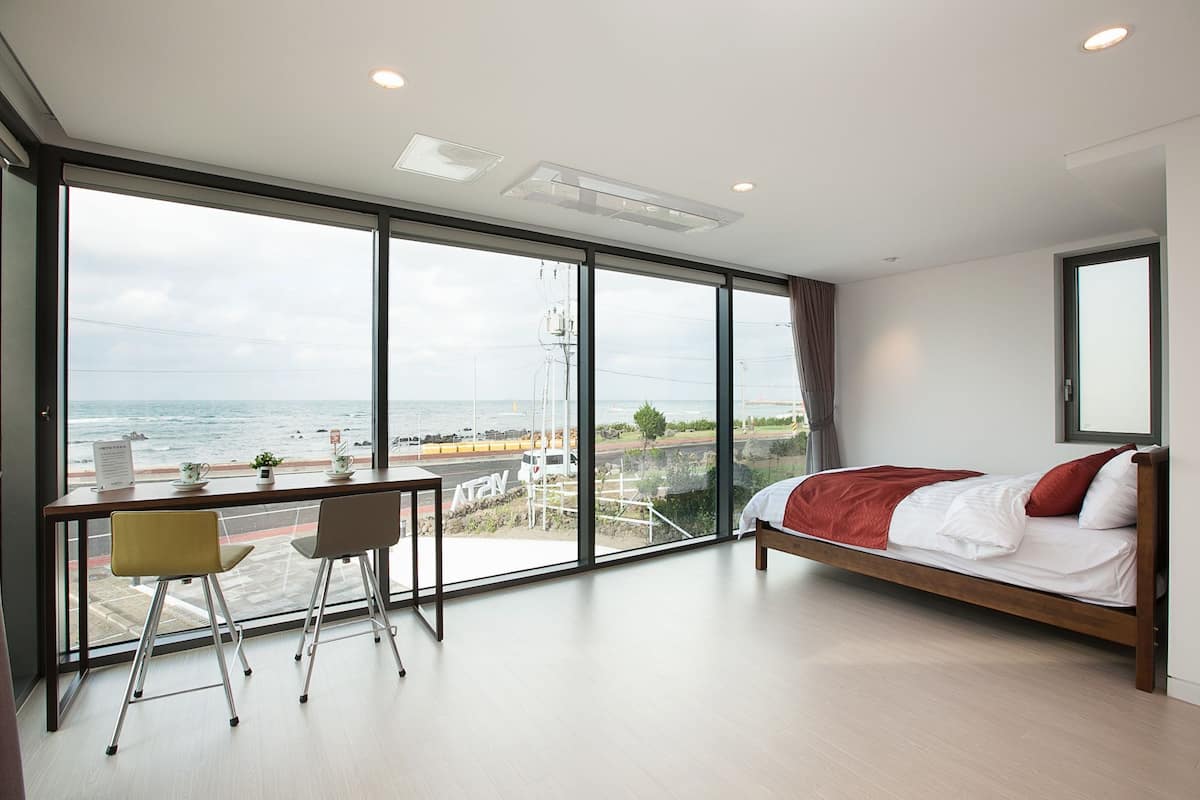 Una habitación de hotel moderna con un ventanal grande, una cama, un escritorio y una silla.