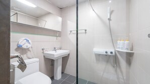 A modern bathroom with a glass-enclosed shower, a sink, and a toilet. There are toiletries on a shelf. - Pension Yeoli (Seogwipo)