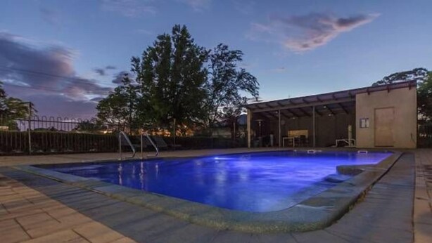 A swimming pool with a covered area and a brick patio. - Banksia Motel Collie (Collie)