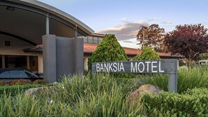 A sign for the Banksia Motel with a modern building in the background. - Banksia Motel Collie (Collie)