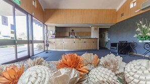 A reception area with a counter, a plant, and a large window. - Banksia Motel Collie (Collie)