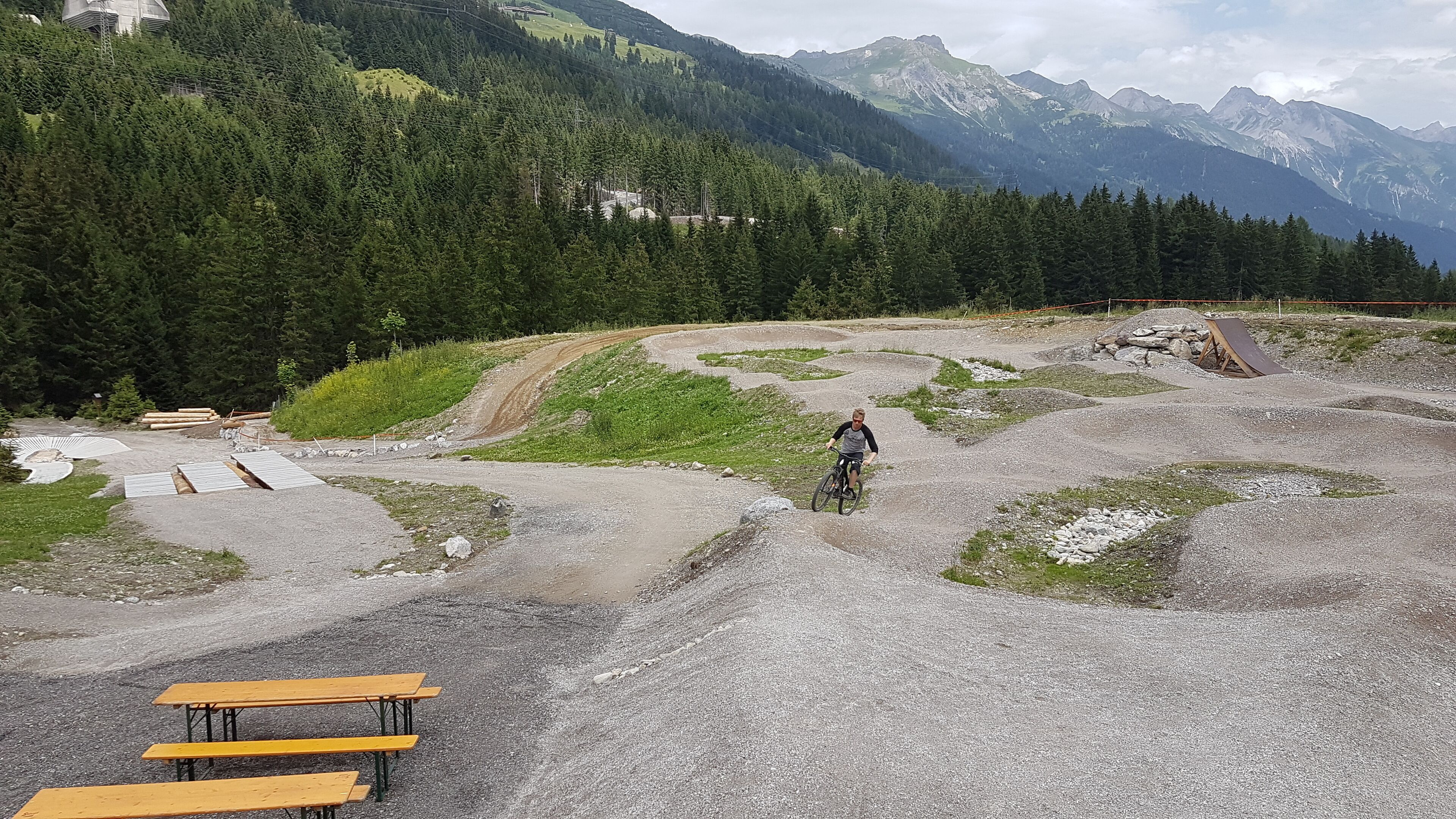 Un sendero para bicicleta de montaña con bancos y una mesa de picnic.