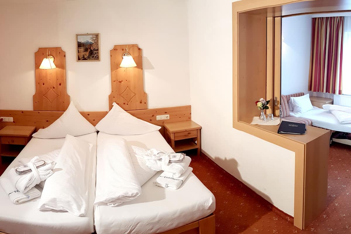 A hotel room with a bed, two bedside tables, a mirror, and a window with curtains.