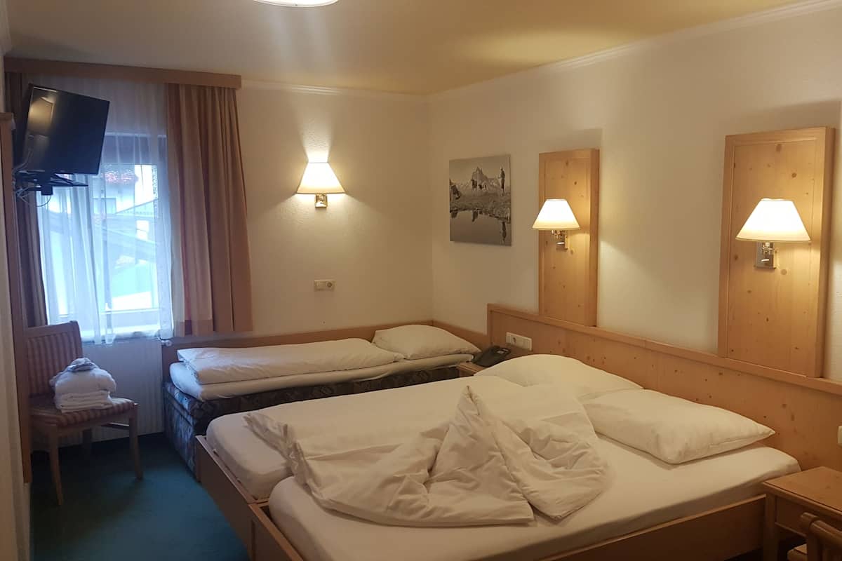 A hotel room with two beds, a TV, and two wall-mounted lamps.