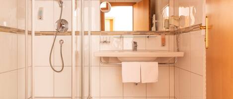 A modern bathroom with a glass shower enclosure, a sink with a towel rack, and a mirror above the sink.