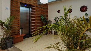 A reception area with a wooden slatted wall, a reception desk, and a digital display. - Hotel Azulejos (San Cristóbal de las Casas)