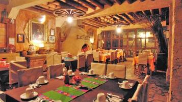 Un restaurant amb taules preparades per dinar, sostre de fusta i interior rústic.