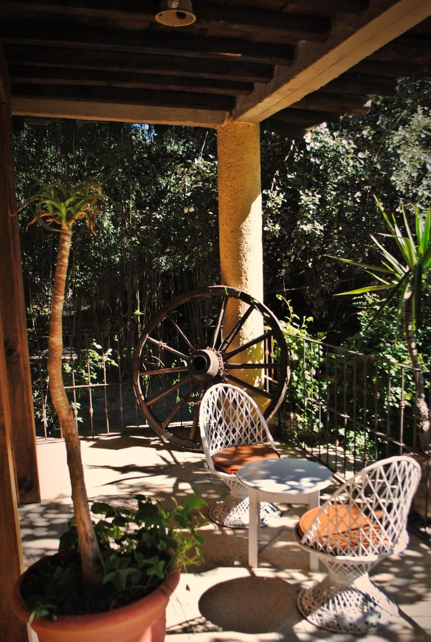 Un espacio de estar al aire libre techado con una mesa, sillas y una gran rueda decorativa.