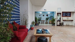 A spacious lobby with a red sofa, a wooden coffee table, and potted plants. - Hotel Azulejos (San Cristóbal de las Casas)