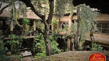 Un patio con un edificio tradicional, una banca y una escalera.
