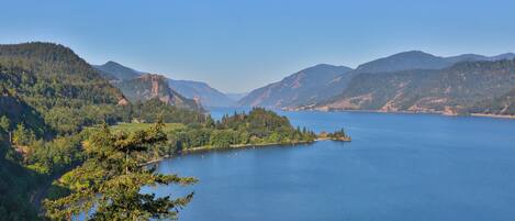 Une vue panoramique d’un lac entouré de montagnes et de forêts denses.