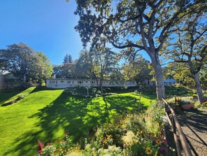 A well-maintained garden with a variety of flowers and a large tree in the foreground. - Westcliff Lodge (Hood River)