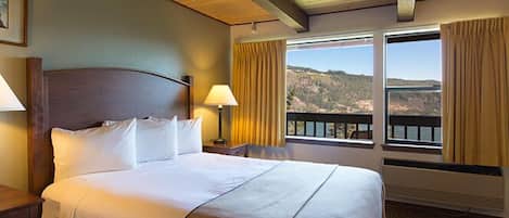 Habitación de hotel con cama, dos lámparas de noche, ventana con vistas al exterior y techo de madera.