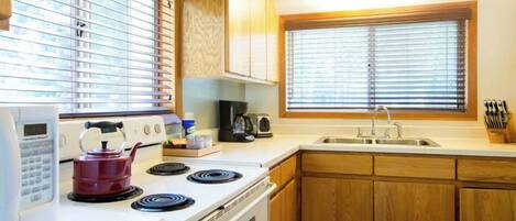 A kitchen with a stove, microwave, and sink.