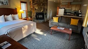 Una habitación acogedora con una cama, un sofá, una mesa de centro y una chimenea.