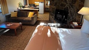 Habitación de hotel con una cama grande, un sofá, una mesa de centro y una pared de acento de piedra.