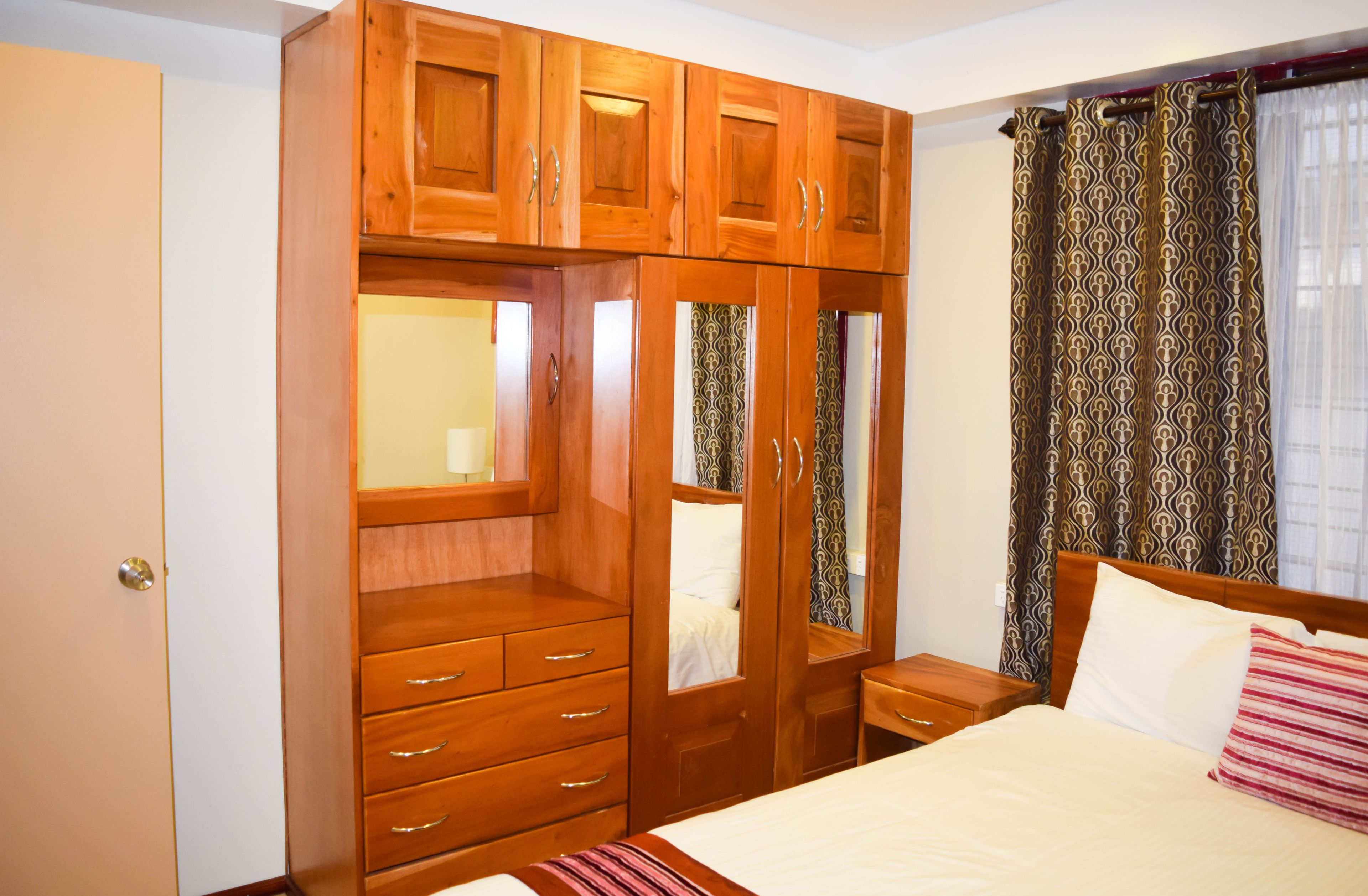 Un dormitorio con un armario de madera, una cama con almohadas y una mesita de noche.
