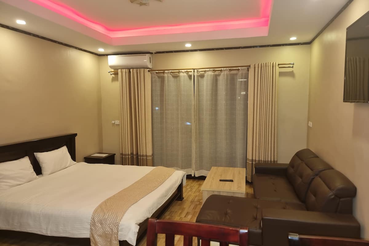 A hotel room with a bed, a sofa, a small table, and a TV.