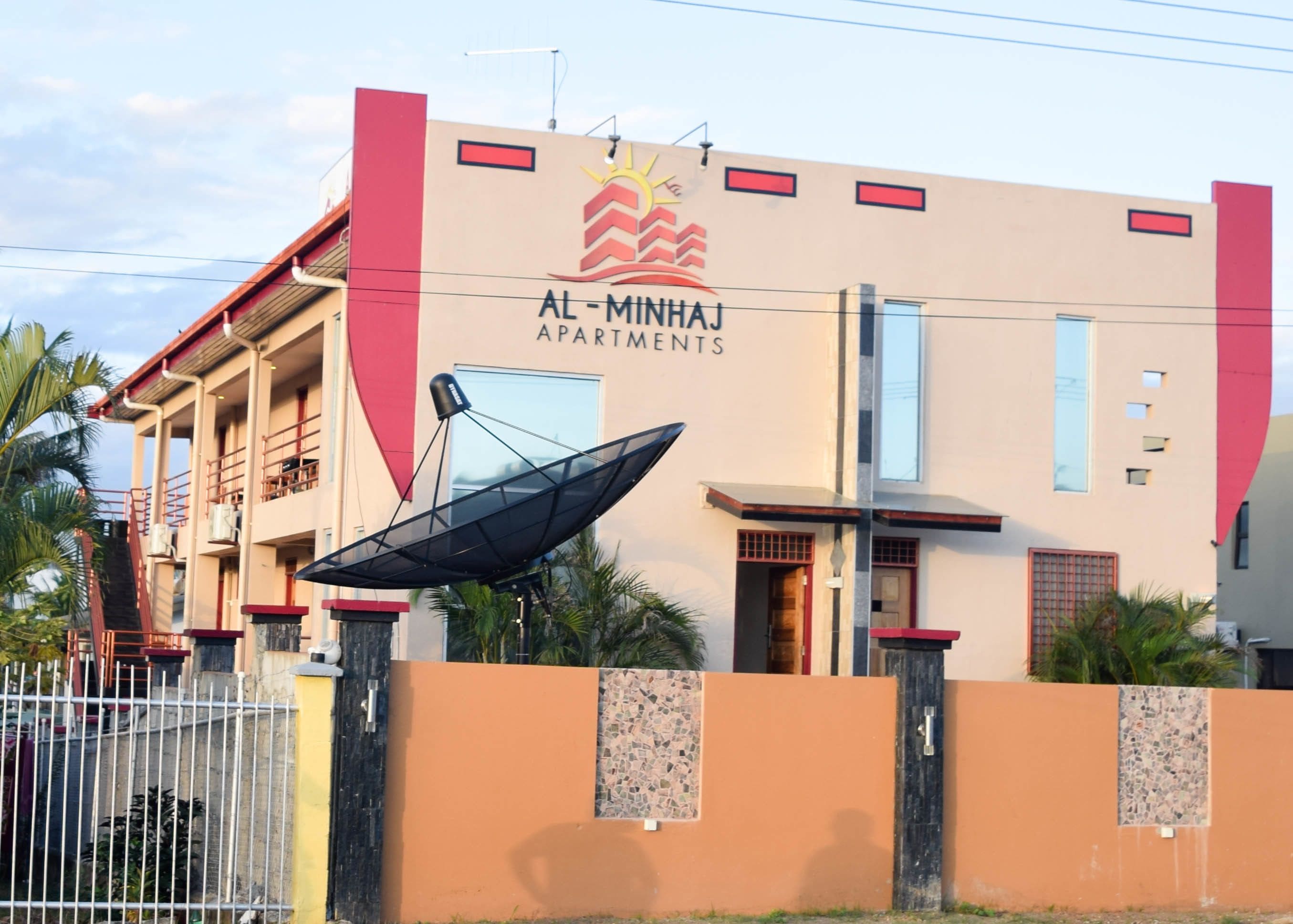 A building with a sign reading "AL-MINHAJ APARTMENTS".