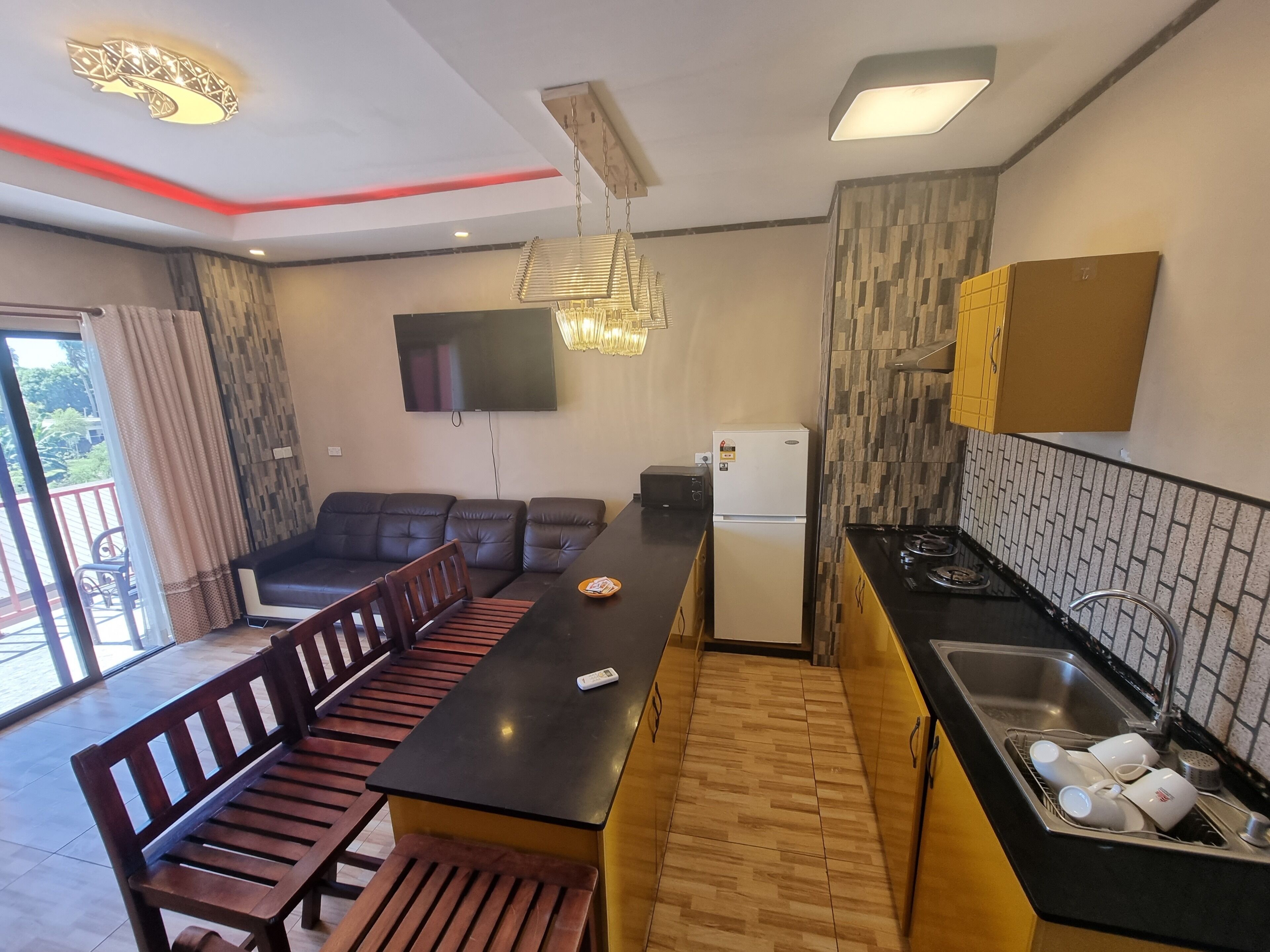 A compact kitchen with a dining area, a refrigerator, a microwave, and a sink with dishes.