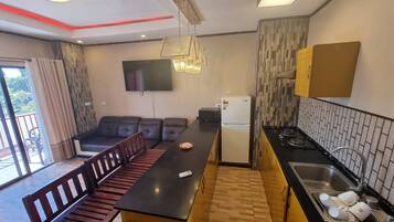 A compact kitchen with a dining area, a refrigerator, a microwave, and a sink with dishes.