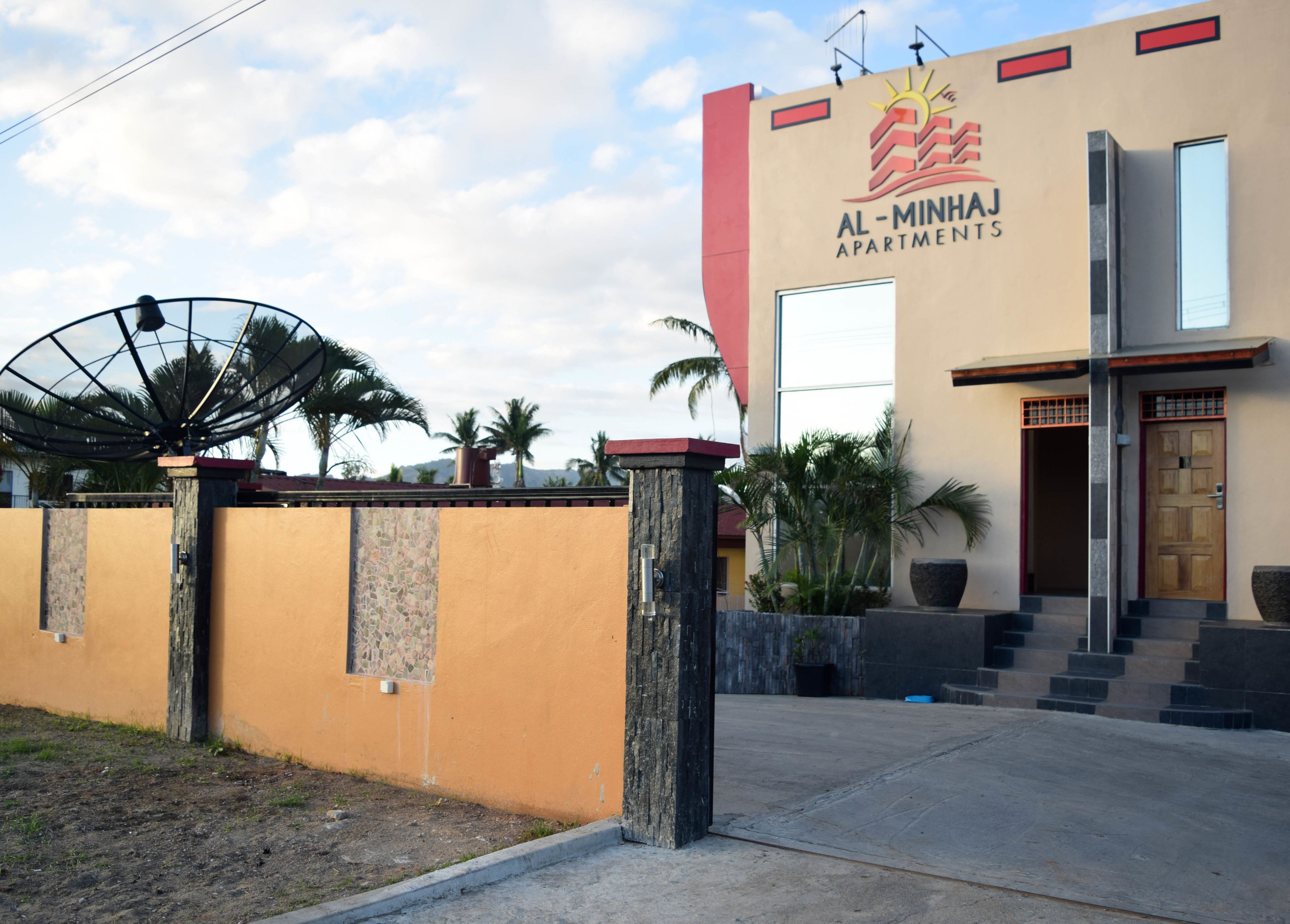 A modern building with a sign reading "Al-Minhaj Apartments".