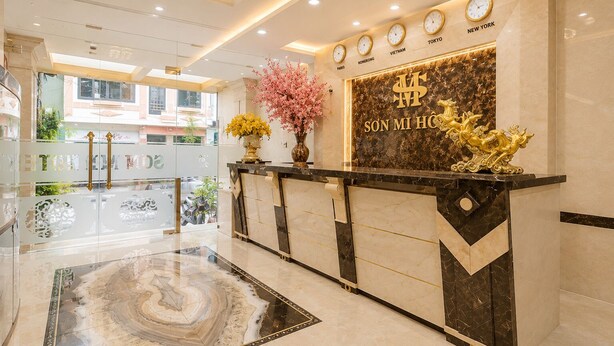A hotel reception desk with a marble floor, a clock displaying multiple time zones, and a decorative golden horse sculpture. - S79 Residences La Rose Spa (Ho Chi Minh City)