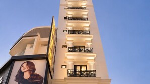 A modern hotel entrance with a prominent sign, a staircase leading to the lobby, and potted plants. - S79 Residences La Rose Spa (Ho Chi Minh City)