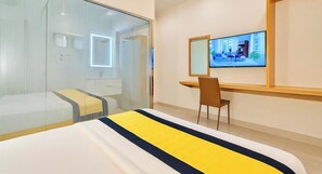 A hotel room with a bed, a desk, a chair, a TV, and a glass partition. - S79 Residences La Rose Spa (Ho Chi Minh City)