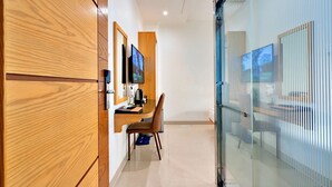 A modern hotel room with wooden cabinetry, a desk with a chair, and a glass partition. - S79 Residences La Rose Spa (Ho Chi Minh City)