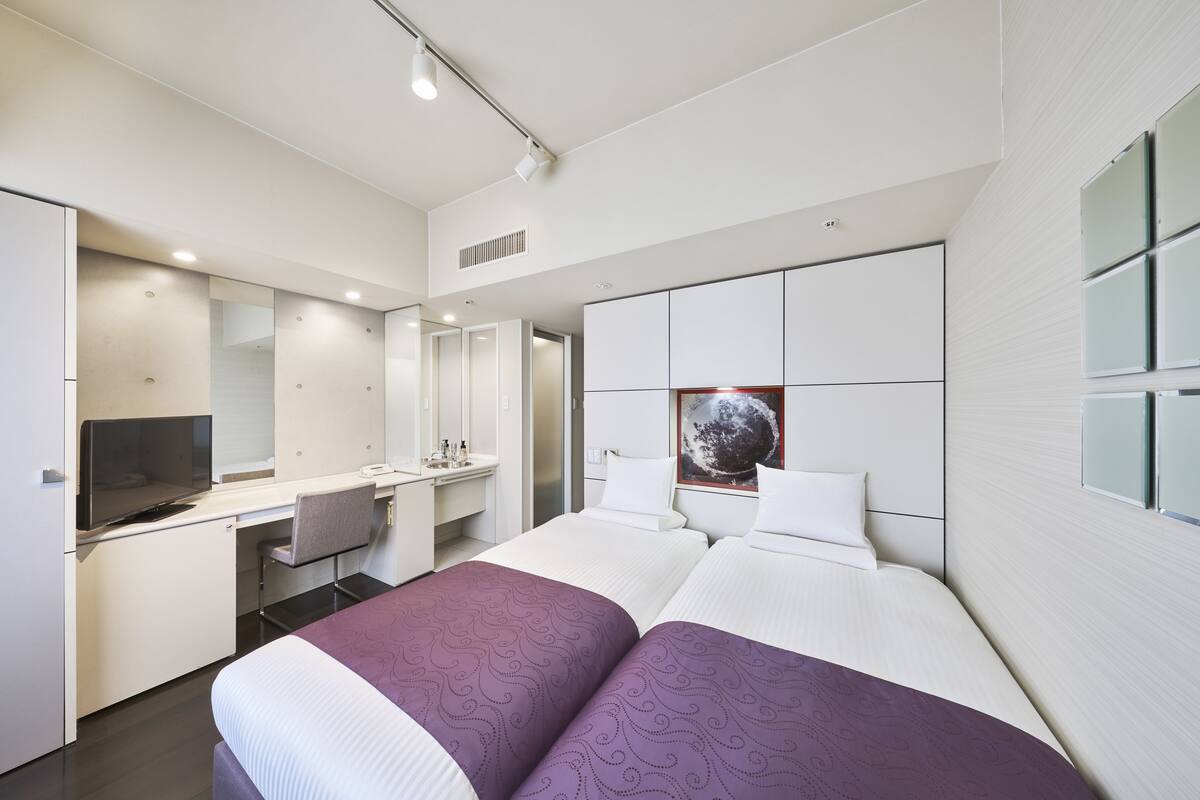 A modern hotel room with a large bed, a desk, a television, and a bathroom.