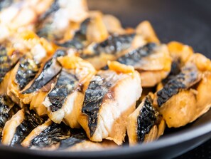 Un plato de pescado a la parrilla con piel oscura y crujiente.