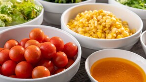 A variety of food items in bowls, including tomatoes, corn, and a salad.