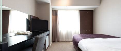 Une chambre d’hôtel comprenant un lit, un bureau avec une télévision, une chaise et une armoire.