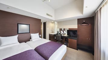 Habitación de hotel con dos camas, un escritorio con televisor, un espejo y un armario.