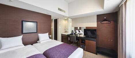 A hotel room with two beds, a desk with a TV, a mirror, and a wardrobe.