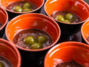 Varios cuencos naranjas con aceitunas verdes.