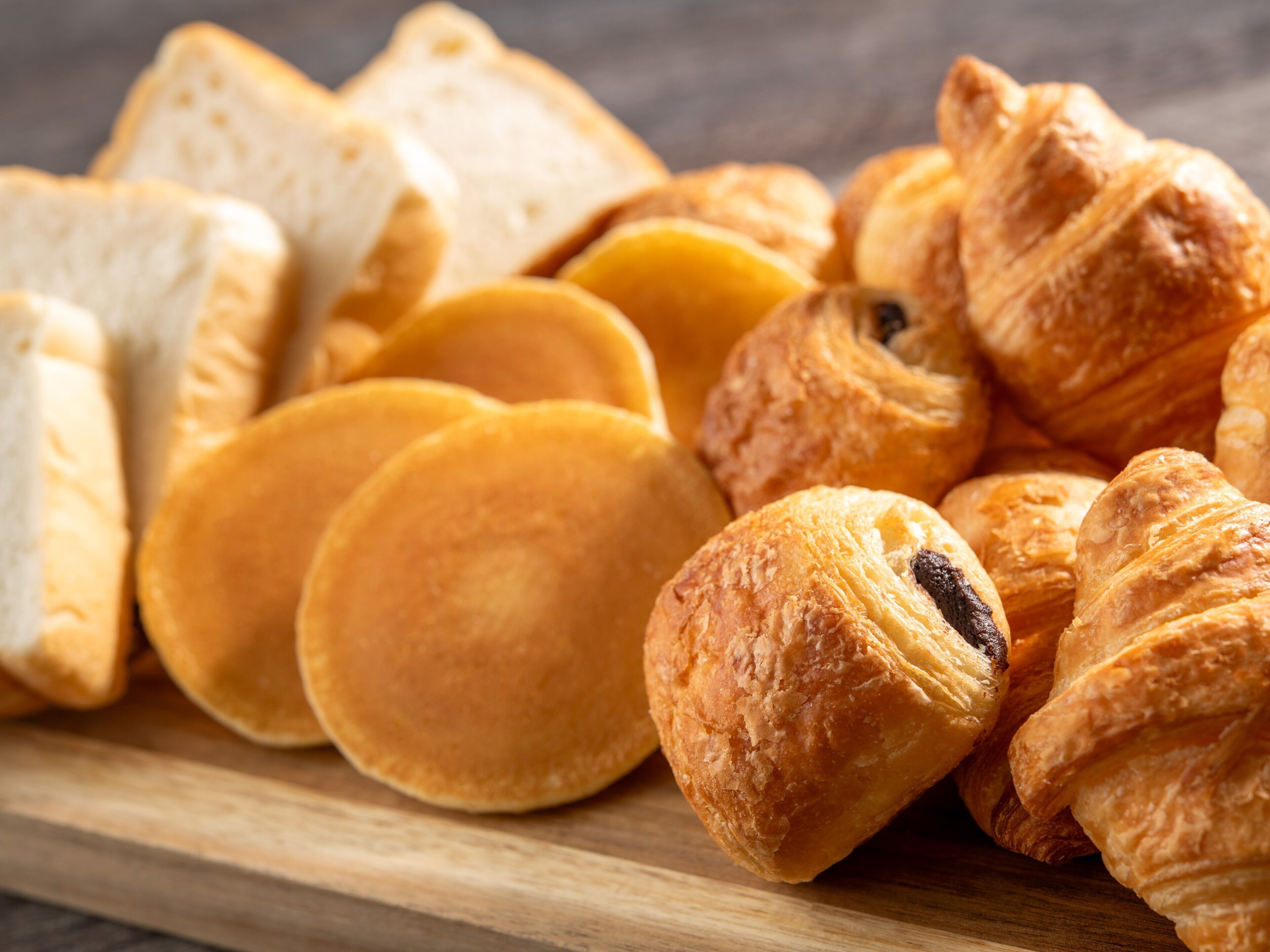 A variety of baked goods including bread and pastries on a wooden surface.