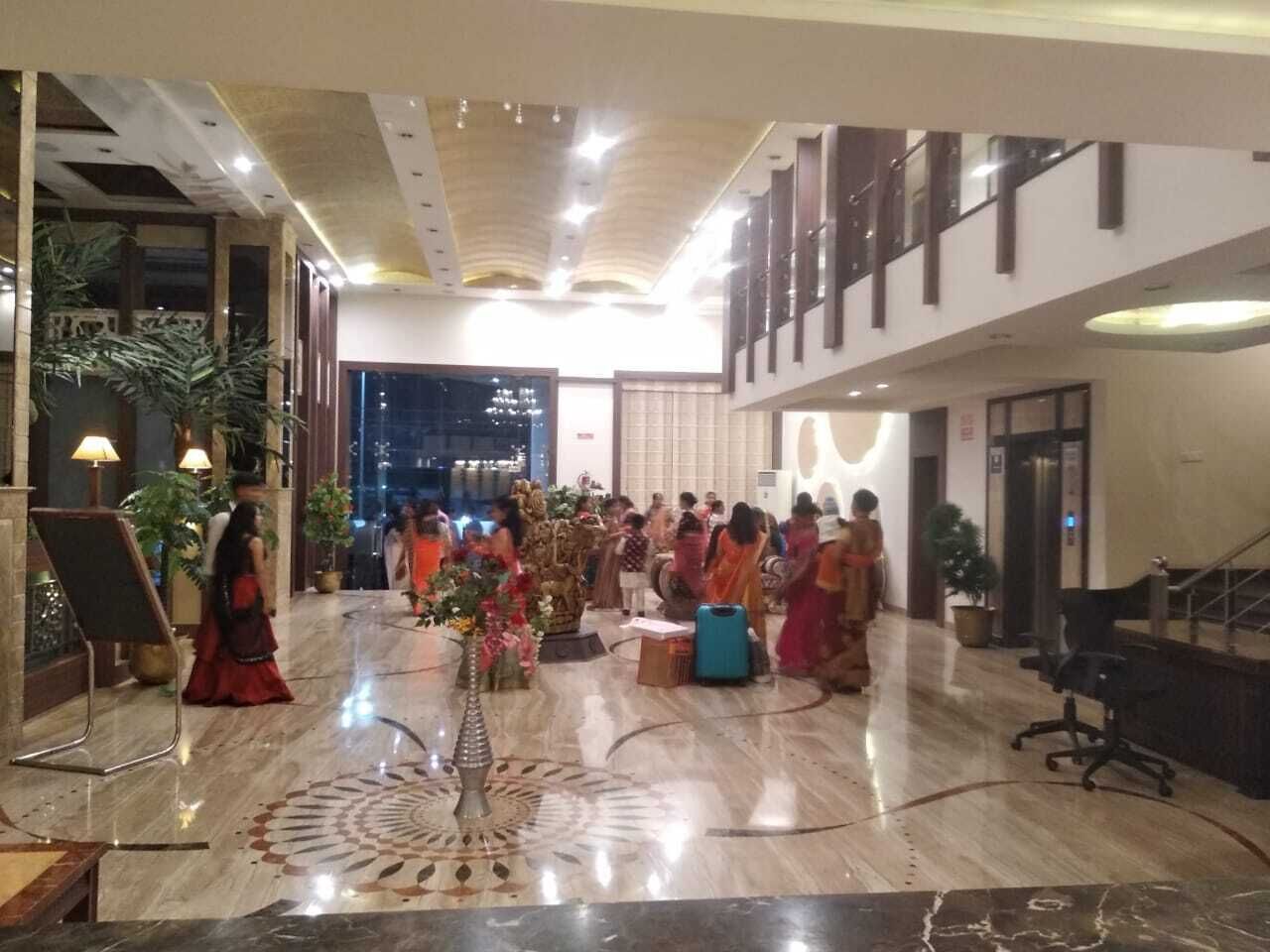 A spacious lobby with a polished marble floor, a reception desk, and a staircase leading to an upper level.