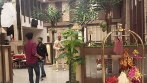 Een hotel lobby met een receptiebalie, potplanten en een decoratieve kar met cadeaus.