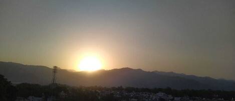 A sunrise over a cityscape with mountains in the background.