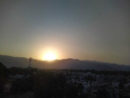 Un amanecer sobre una ciudad con montañas al fondo.