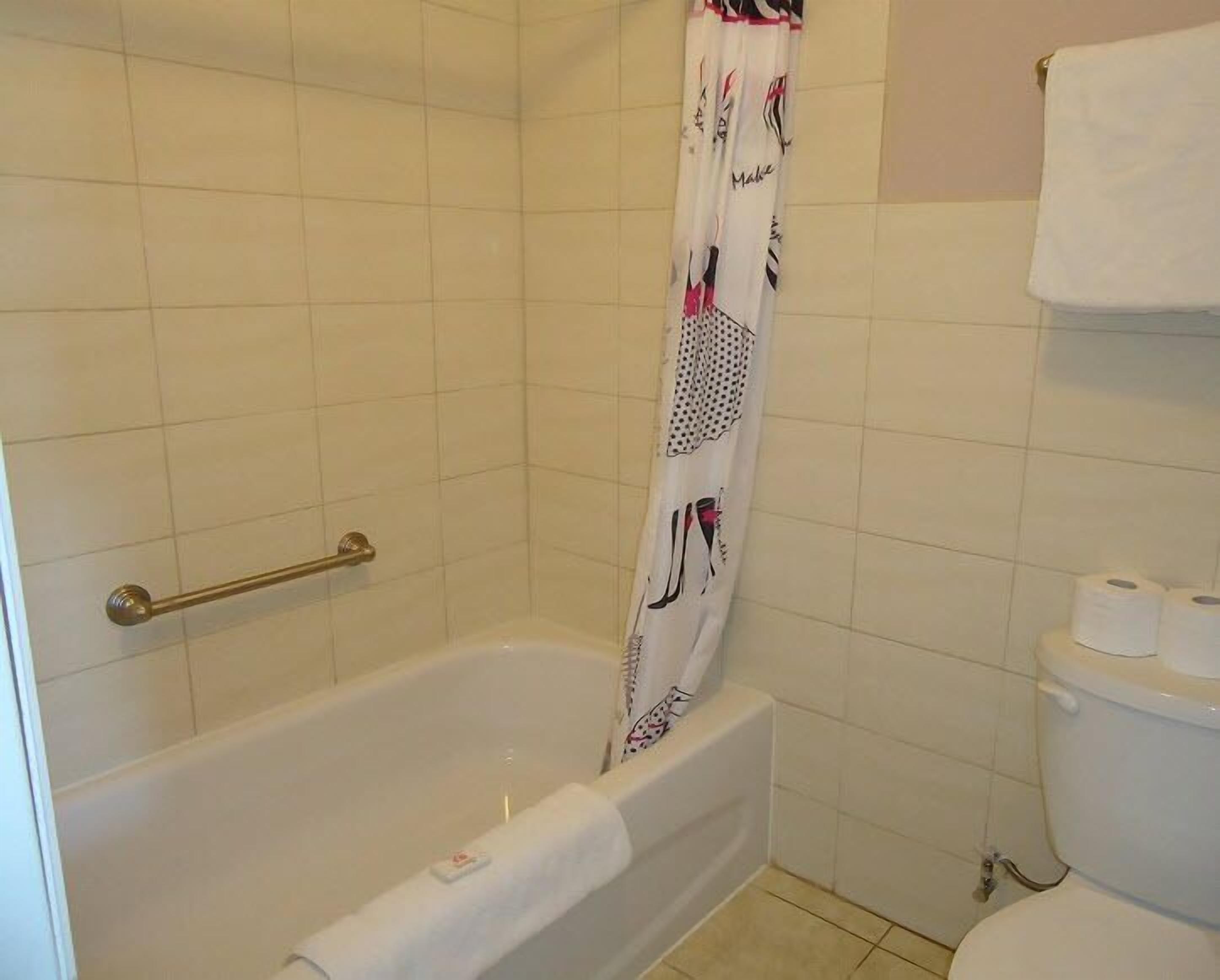 A bathroom with a bathtub, a shower curtain, a towel rack, and a toilet.