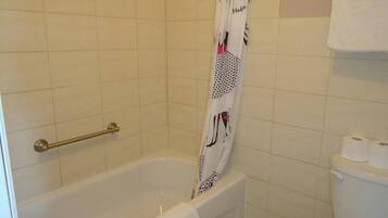 A bathroom with a bathtub, a shower curtain, a towel rack, and a toilet.